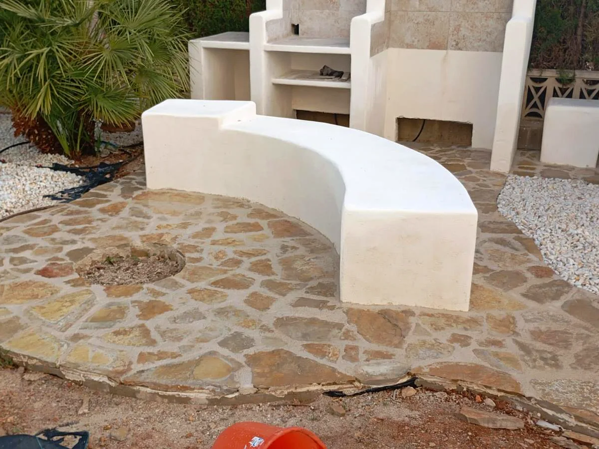 Curved masonry bench and irregular natural stone paving in a Marina Alta villa garden — Grupo Topo Reformas
