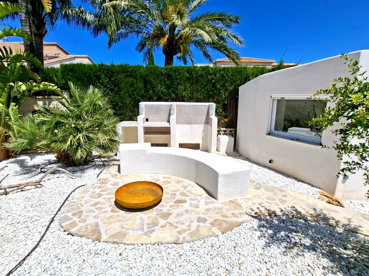 Mediterranean garden chill-out area with whitewashed masonry bench, natural stone paving and white gravel — Grupo Topo Reformas