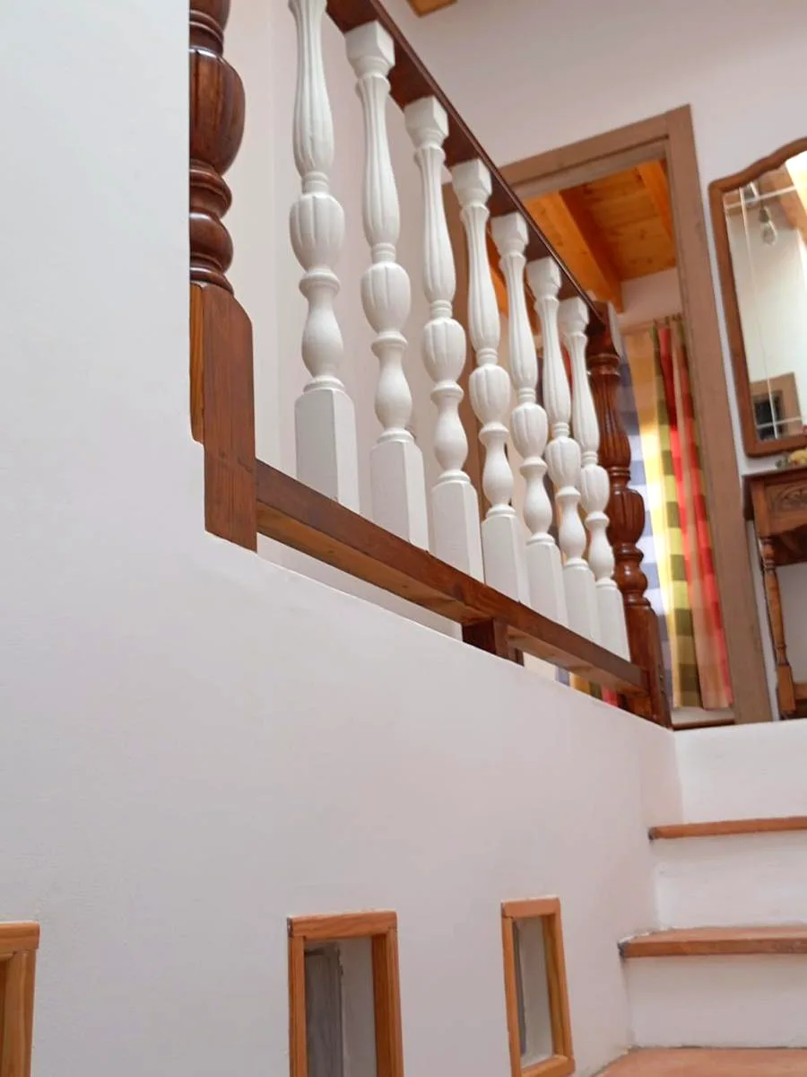 Interior staircase with white turned balustrade and wooden handrail in a traditional Marina Alta house — Grupo Topo Reformas